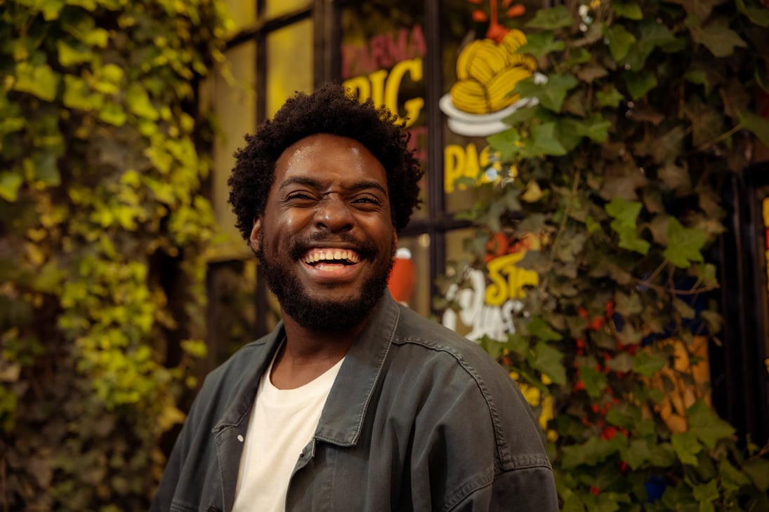 a photo of a smiling person with an afro in front of a window background